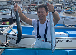 店主が漁港で獲れたて魚を披露している画像
